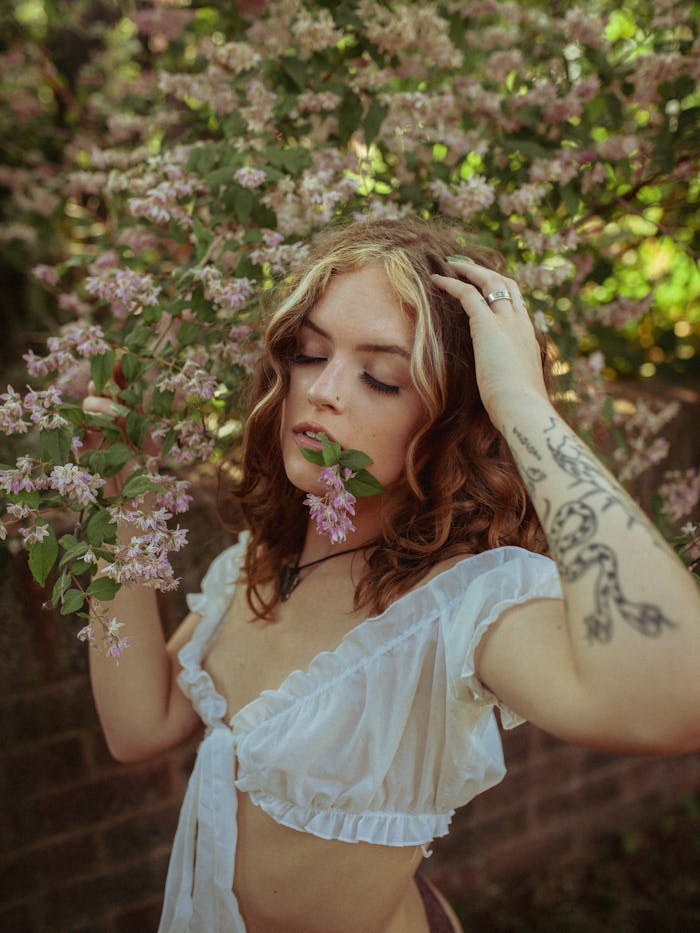A serene portrait of a woman surrounded by pink blossoms, capturing nature's tranquility.